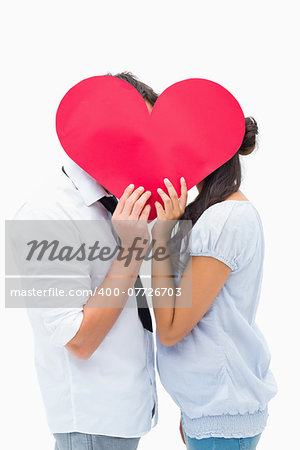 Couple covering their kiss with a heart on white background