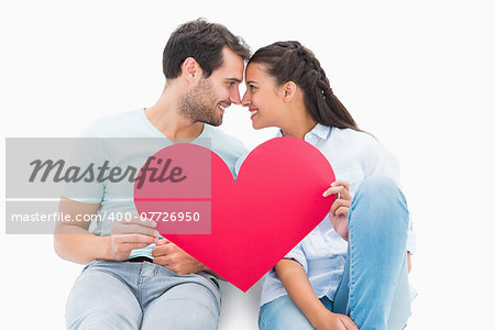 Cute couple sitting holding red heart on white background