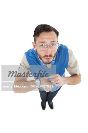 Geeky hipster looking at camera pointing at watch on white background