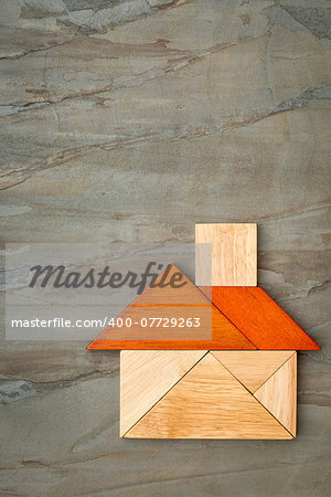 abstract picture of a house built from seven tangram wooden pieces against slate rock background, a traditional Chinese puzzle game, the artwork copyright by the photographer