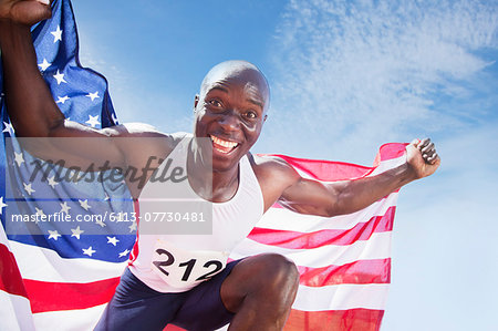 Portrait of enthusiastic track and field athlete holding American flag