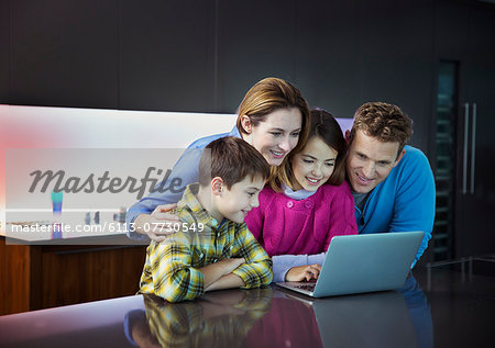 Family using laptop together in kitchen