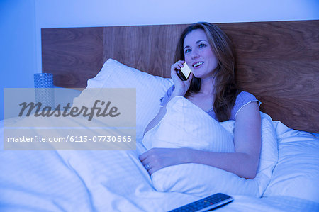 Woman talking on cell phone in bed