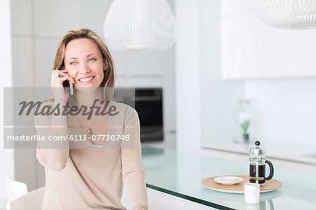 Woman talking on cell phone at breakfast table