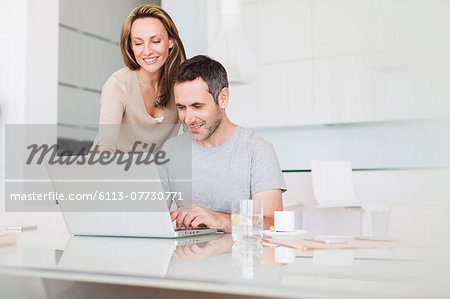 Couple using laptop at breakfast table