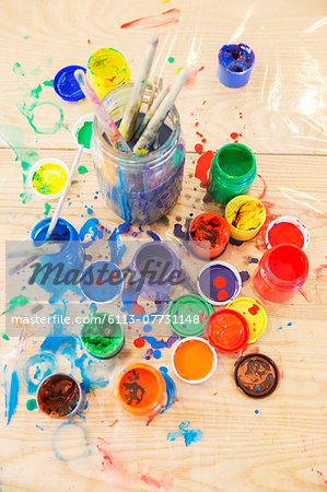 Jars of paint and paintbrushes on wooden table