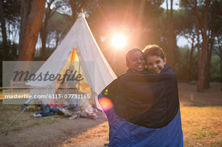 Boys wrapped in blanket at campsite