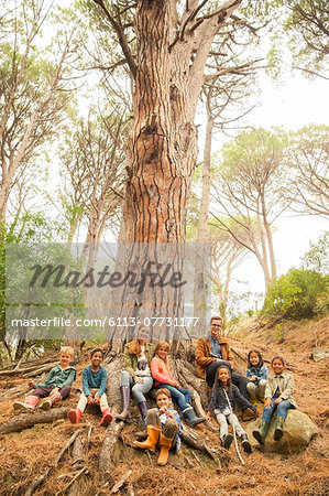 Students and teachers sitting on tree in forest