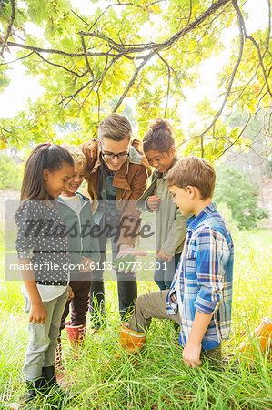 Students and teacher examining leaf outdoors