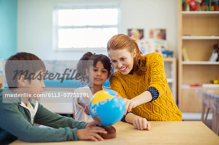 Students and teacher examining globe in classroom Students and teacher examining globe in classroom