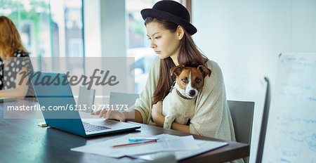 Woman holding dog and working in office