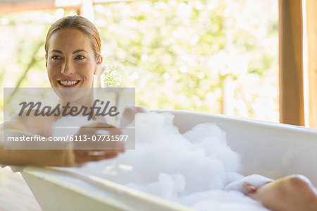Woman having champagne in bubble bath