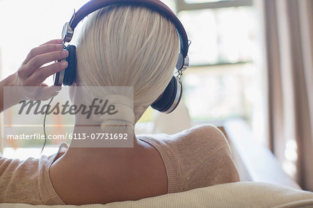 Woman listening to headphones on sofa