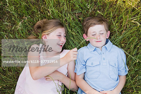 Two children, brother and sister lying side by side on the grass