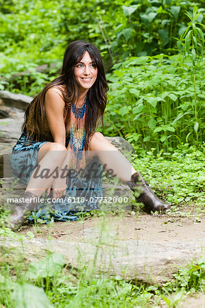 A woman with long brown hair outdoors in woodland.