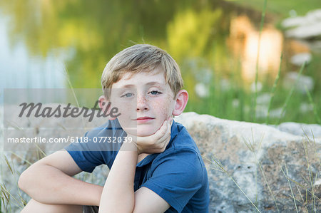 Head and shoulders portrait of a young boy sitting with his chin resting on his hand.