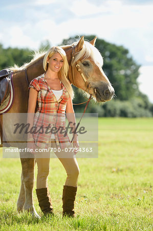 Close-up portrait of a young woman standing beside her Haflinger horse in a field in summer, Upper Palatinate, Bavaria, Germany