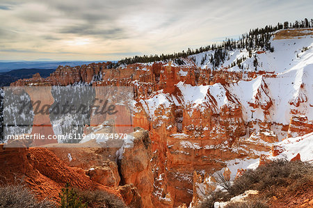 Top-heavy hoodoo, pine trees and cliffs with snow and a cloudy sky, Agua Canyon, Bryce Canyon National Park, Utah, United States of America, North America