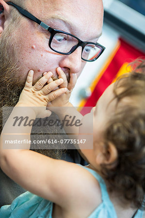 Close up of baby girl with hands over man's mouth