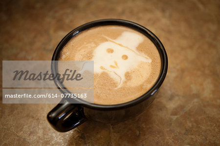 Close up of cup on cafe counter decorated with foam face