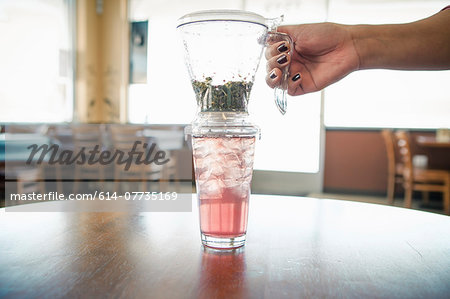 Female hand with iced herbal tea and filter in cafe Female hand with iced herbal tea and filter in cafe