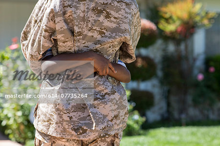 Cropped rear view of female soldier hugging son on homecoming