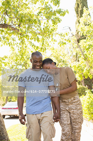Female soldier resting head on husbands shoulder whilst strolling on homecoming
