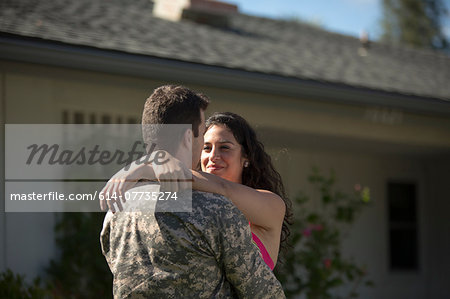 Male soldier hugging wife in garden on homecoming