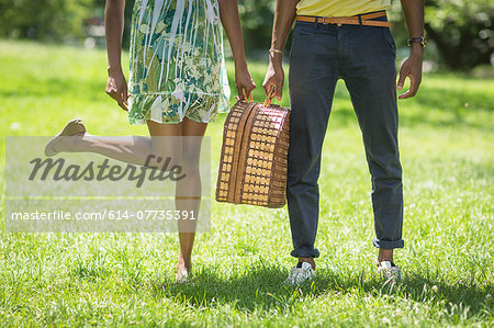 Cropped image of young couple with picnic basket in park