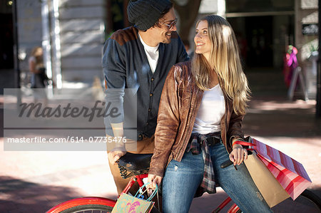 Smiling young woman and boyfriend leaning on bicycle, Cape Town, South Africa