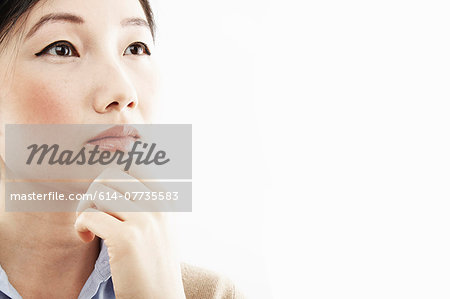 Close up studio portrait of young woman with hand on chin