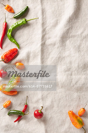 Selection of summer chilli peppers on an ivory linen surface