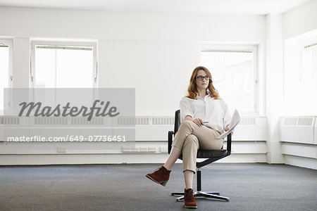 Mid adult businesswoman on office chair in new office