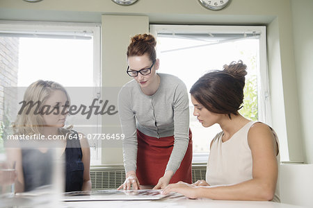 Three businesswomen looking at blueprint in office