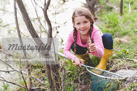 Portrait of girl holding up frog and fishing net