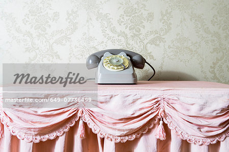 Still life of vintage telephone on frilly tablecloth