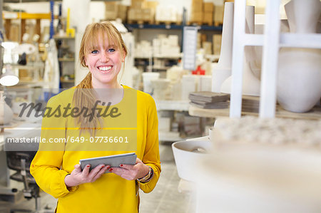 Female potter using digital tablet in ceramic workshop