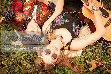 Hippy girls lying in field with guitar