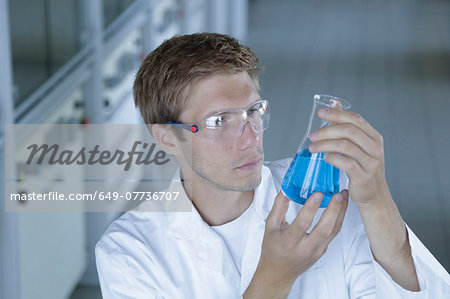 Male scientist holding up erlenmeyer flask in lab Male scientist holding up erlenmeyer flask in lab