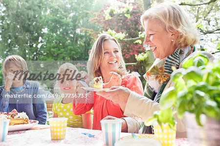 Mother serving birthday cake to family at birthday party