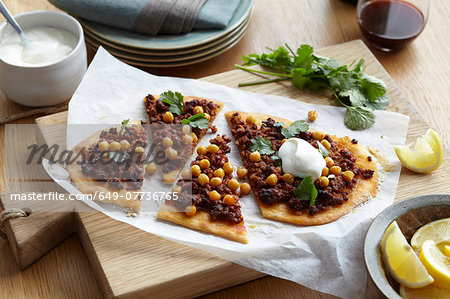 Middle eastern lamb and chickpea pizza with herb garnish and lemon slices