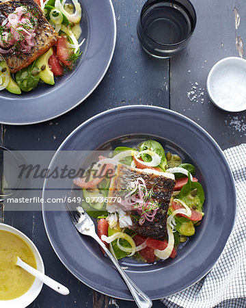 Plate of barramundi fish with vegetables and a herb garnish