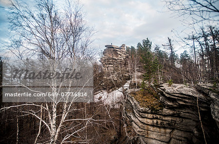Climber on top of rock formation in mountain forest