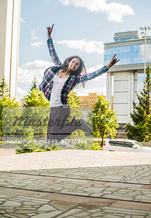 Young woman jumping mid air in city