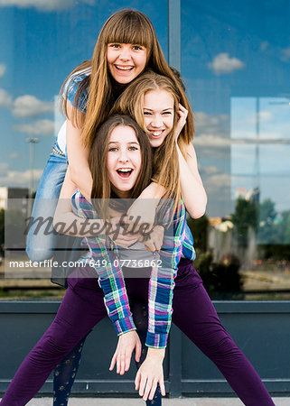 Three young women stacked on top of each other in city