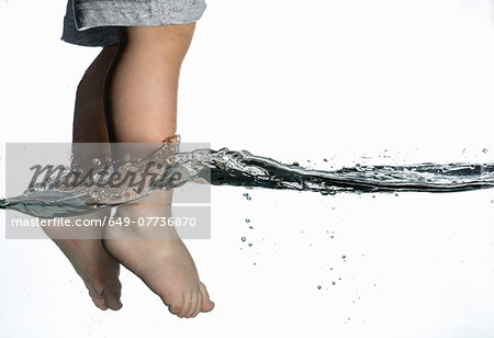 Surface level view of toddlers feet dangling in clear water