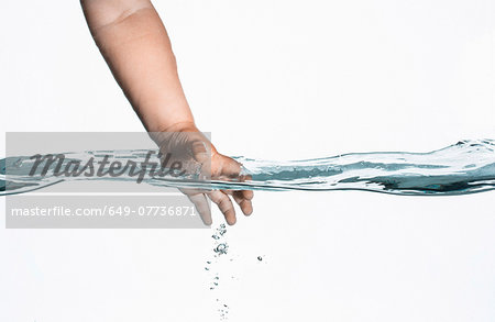 Surface level view of toddlers hand reaching into clear water