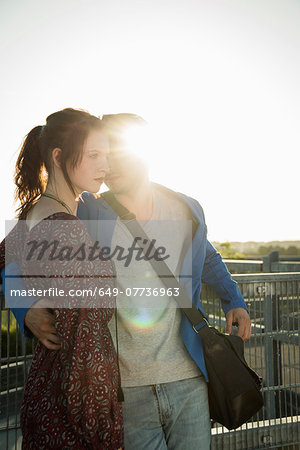 Romantic young couple leaning against fence on rooftop