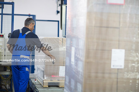 Worker using machine in paper packaging factory