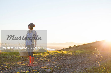 Young woman standing on hill at sunset